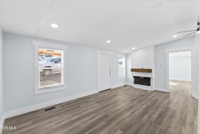 unfurnished living room featuring visible vents, lofted ceiling, wood finished floors, a fireplace, and recessed lighting