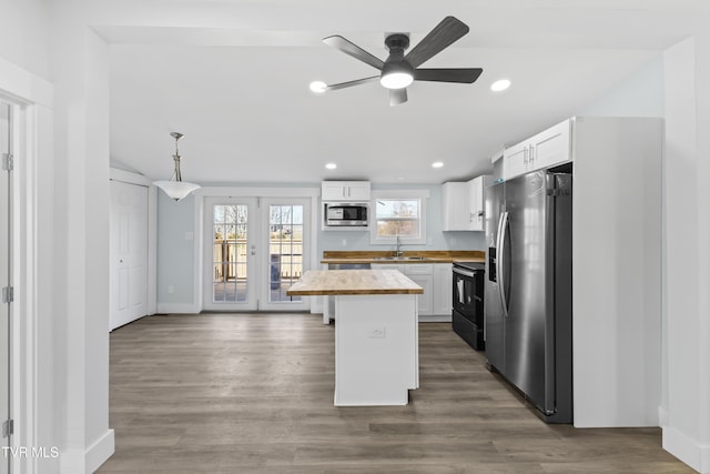 kitchen with a center island, stainless steel appliances, wooden counters, white cabinetry, and a sink