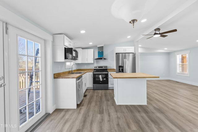 kitchen featuring appliances with stainless steel finishes, a sink, wood counters, and wall chimney exhaust hood