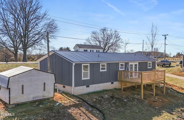 back of property with metal roof, crawl space, board and batten siding, and a wooden deck