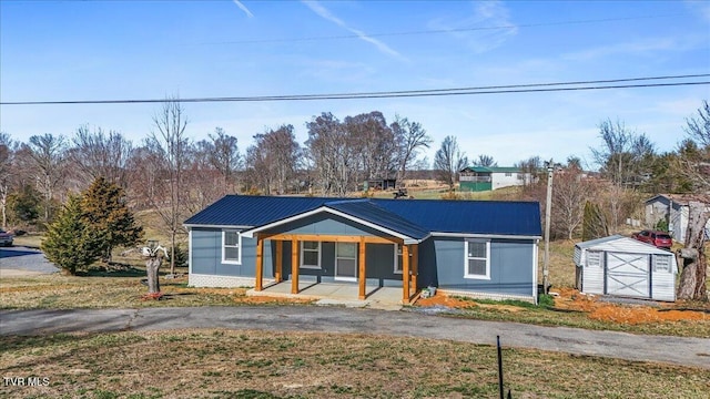 view of front of home featuring a porch, an outbuilding, metal roof, and a shed