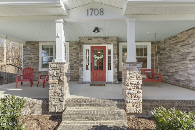 property entrance with stone siding and a porch