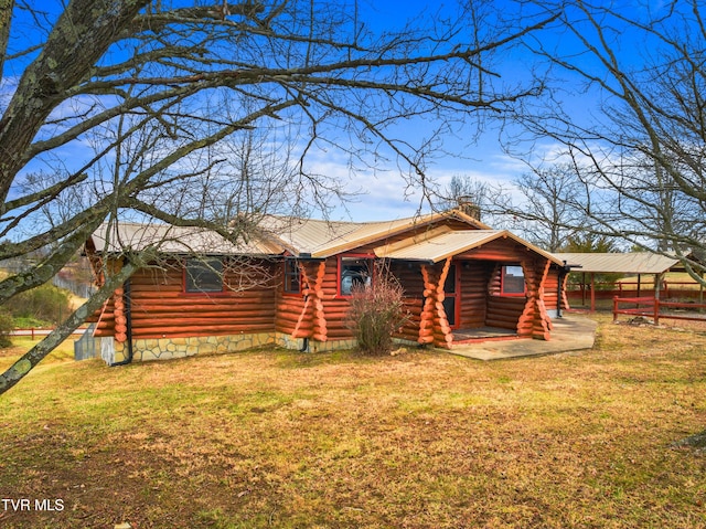 back of property featuring a chimney, log siding, and a lawn