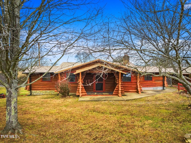 back of house with a yard, a chimney, and log siding