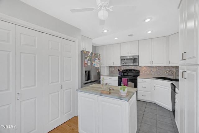 kitchen featuring black appliances, decorative backsplash, white cabinets, and a sink