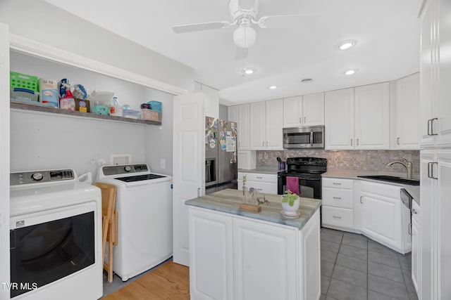 kitchen featuring decorative backsplash, appliances with stainless steel finishes, washing machine and dryer, white cabinetry, and a sink