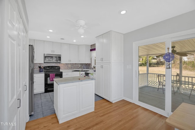 kitchen with a sink, white cabinets, light countertops, appliances with stainless steel finishes, and tasteful backsplash