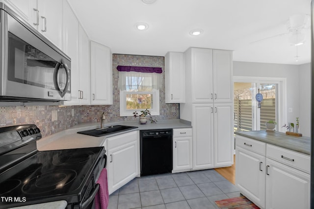 kitchen with black appliances, white cabinets, a sink, and light countertops