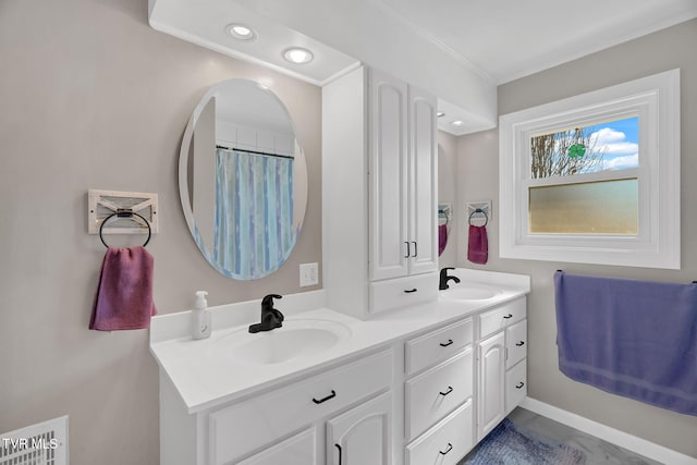 full bath featuring double vanity, crown molding, baseboards, and a sink