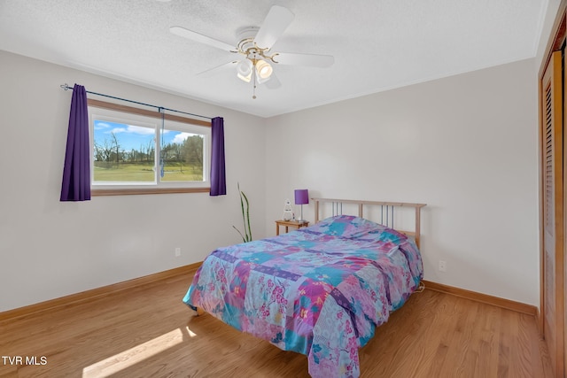 bedroom featuring a textured ceiling, baseboards, and wood finished floors