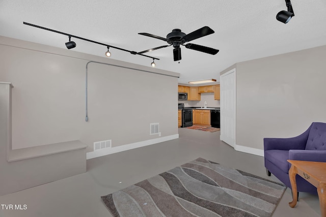 living area with baseboards, finished concrete floors, visible vents, and a textured ceiling