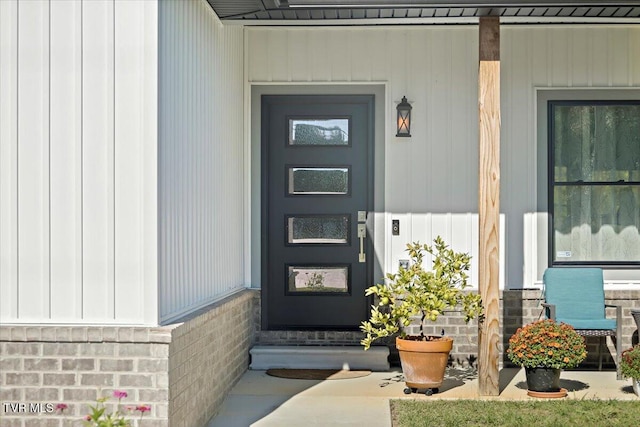 doorway to property featuring brick siding and board and batten siding