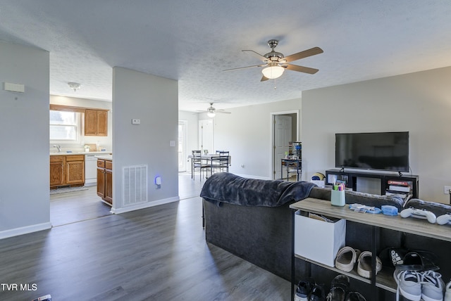 living area featuring a textured ceiling, dark wood-style flooring, visible vents, and baseboards