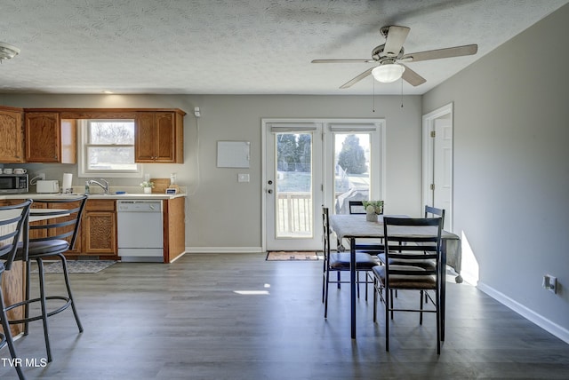 dining space with a ceiling fan, a textured ceiling, baseboards, and wood finished floors