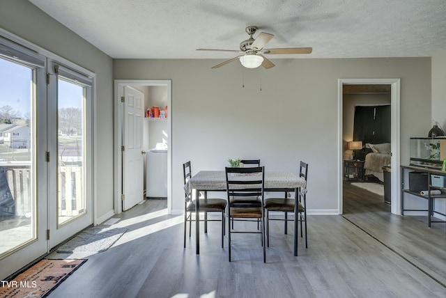 dining space with baseboards, a textured ceiling, washer / clothes dryer, and wood finished floors