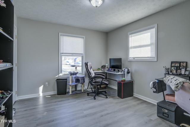 office featuring plenty of natural light, a textured ceiling, baseboards, and wood finished floors