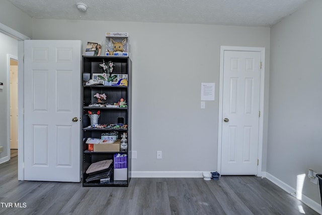 bedroom featuring a textured ceiling, wood finished floors, and baseboards