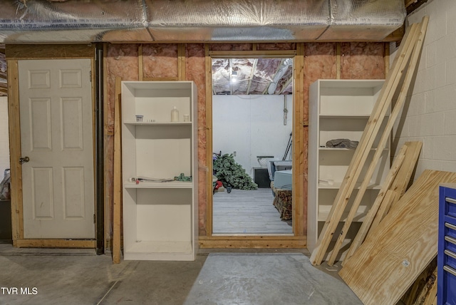 interior space with concrete block wall and unfinished concrete floors