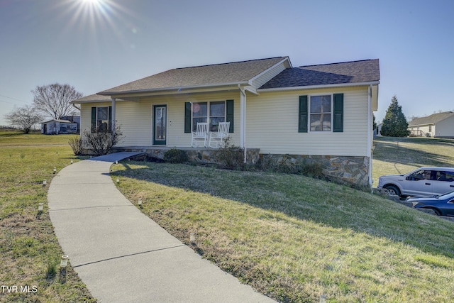 ranch-style house with a front lawn, roof with shingles, and a porch