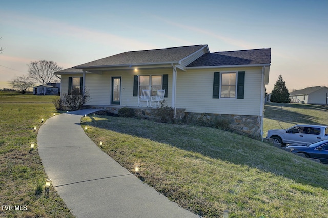 ranch-style house with a shingled roof, a porch, and a front lawn