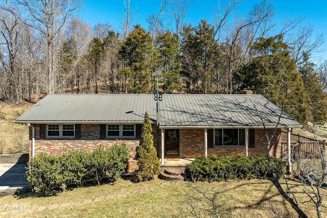 ranch-style home with metal roof, brick siding, and a front yard