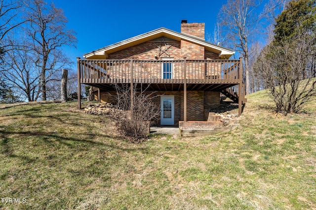 rear view of property with a chimney, a deck, a lawn, and brick siding