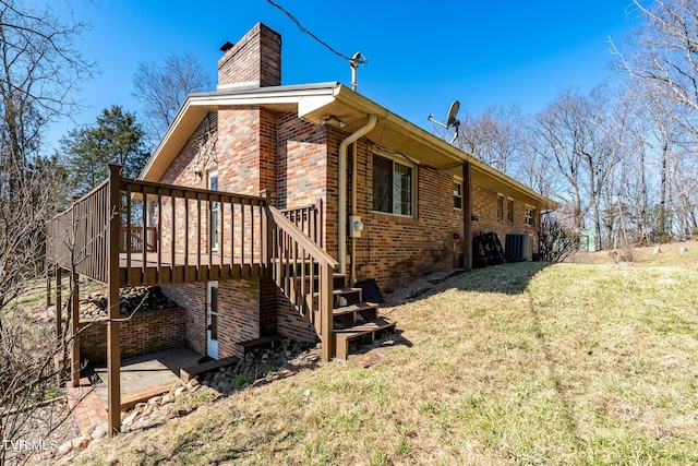 view of property exterior featuring brick siding, stairs, a yard, a wooden deck, and a chimney