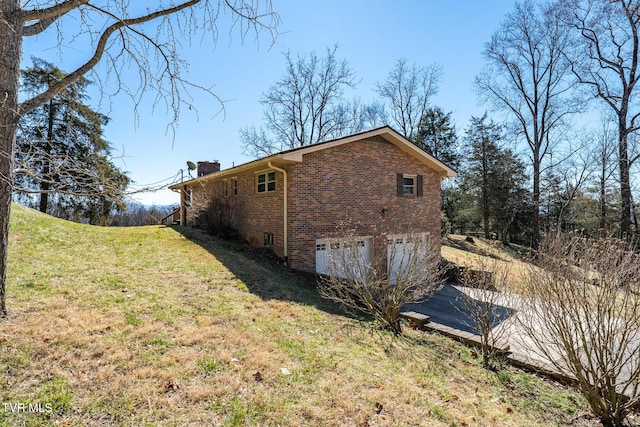 view of home's exterior featuring a yard, brick siding, and a chimney