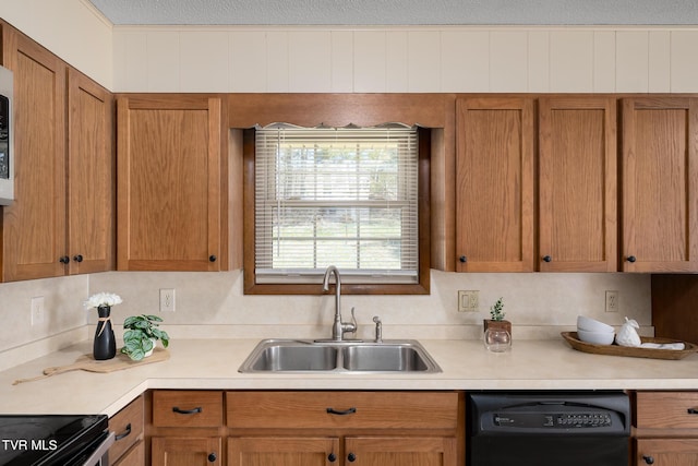 kitchen featuring black dishwasher, light countertops, and a sink