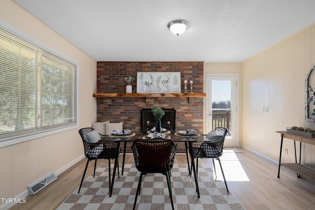 interior space with baseboards, visible vents, wood finished floors, a textured ceiling, and a fireplace