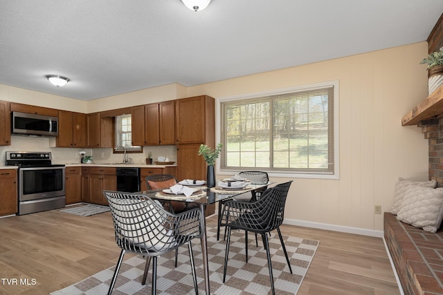 kitchen with light wood-type flooring, stainless steel appliances, a sink, and light countertops