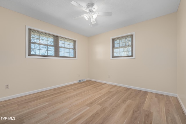 empty room with a ceiling fan, light wood-style flooring, visible vents, and baseboards