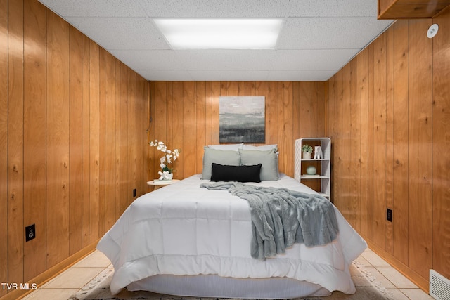 bedroom with a paneled ceiling, wooden walls, and visible vents