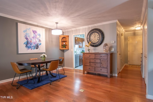 dining area featuring baseboards, wood finished floors, and crown molding