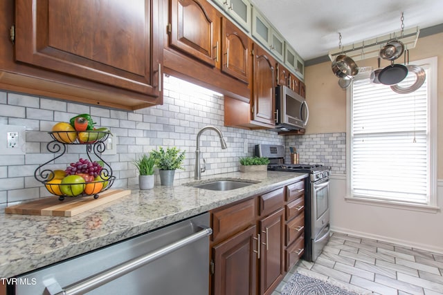 kitchen featuring stainless steel appliances, a sink, a wealth of natural light, and decorative backsplash