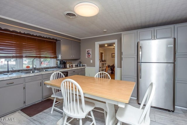 kitchen with visible vents, a sink, gray cabinets, and freestanding refrigerator