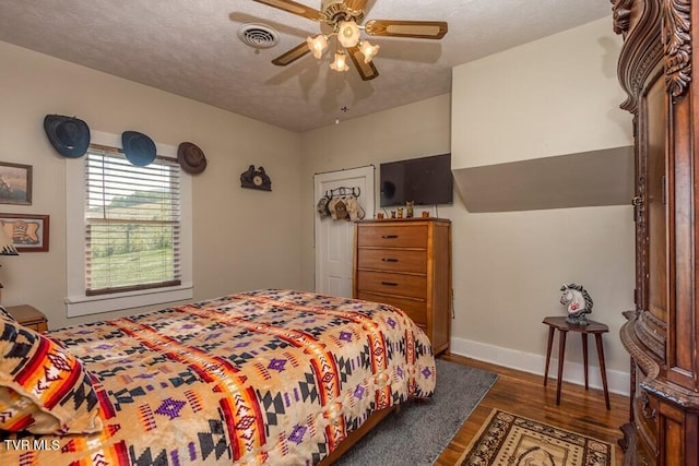 bedroom with visible vents, a ceiling fan, a textured ceiling, wood finished floors, and baseboards