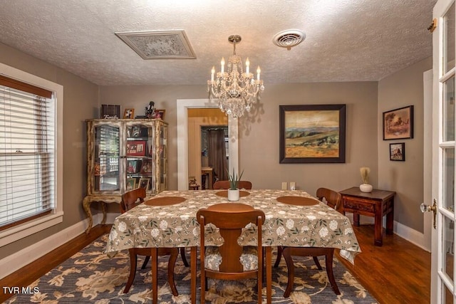 dining room with dark wood-style flooring, visible vents, an inviting chandelier, a textured ceiling, and baseboards