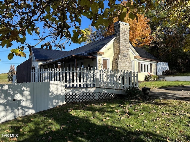 view of side of home with metal roof, a yard, a chimney, and a wooden deck