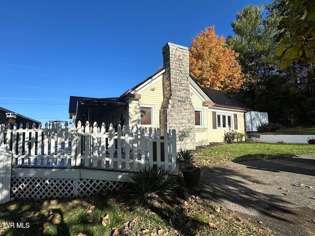 view of side of home with metal roof, a chimney, and a wooden deck