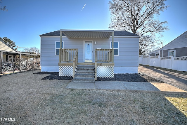 rear view of house with roof with shingles, fence, and a wooden deck