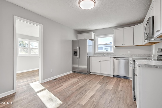 kitchen featuring visible vents, white cabinetry, light countertops, appliances with stainless steel finishes, and light wood-type flooring