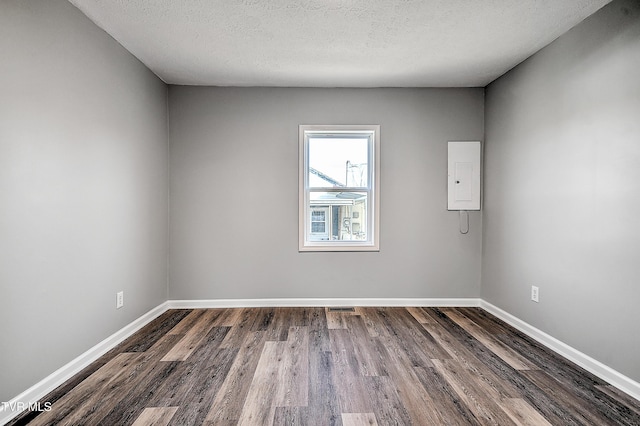 spare room featuring dark wood finished floors, visible vents, a textured ceiling, electric panel, and baseboards