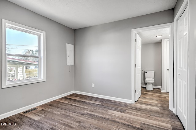 unfurnished bedroom featuring a textured ceiling, wood finished floors, visible vents, and baseboards