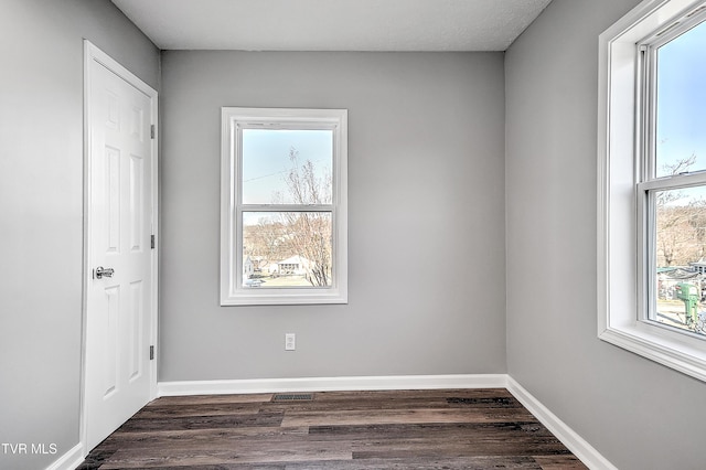 empty room with dark wood-style flooring and baseboards