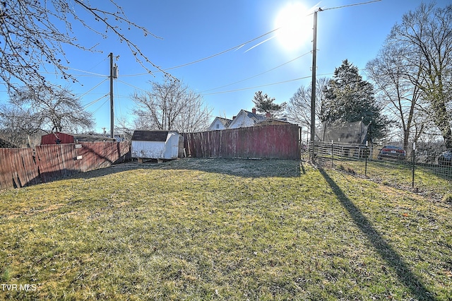 view of yard featuring an outbuilding, a fenced backyard, and a storage unit