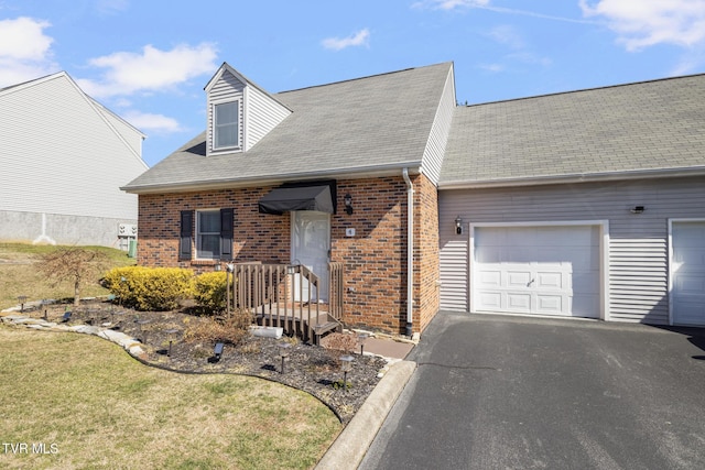 view of front of property featuring aphalt driveway, a front yard, brick siding, and an attached garage