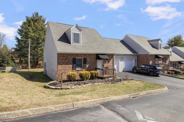 view of front facade with aphalt driveway, a front lawn, brick siding, and an attached garage