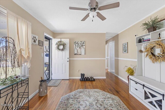 entrance foyer featuring ornamental molding, a textured ceiling, baseboards, and wood finished floors