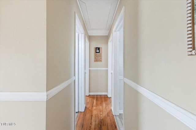 hallway with attic access and wood finished floors